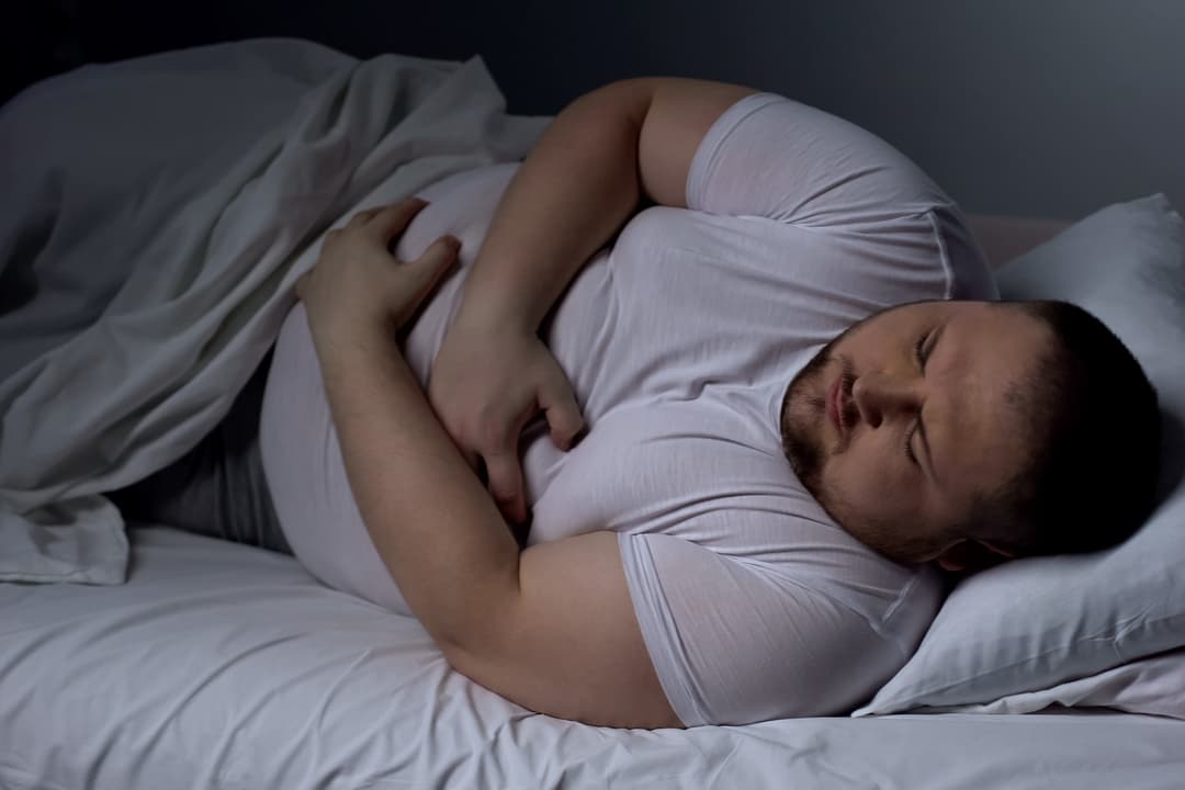 overweight man struggling to sleep