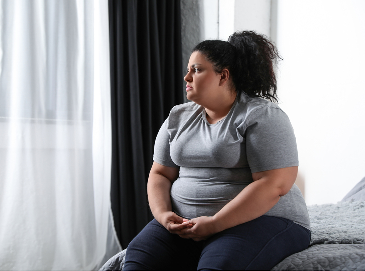 obese woman sitting on edge of bed